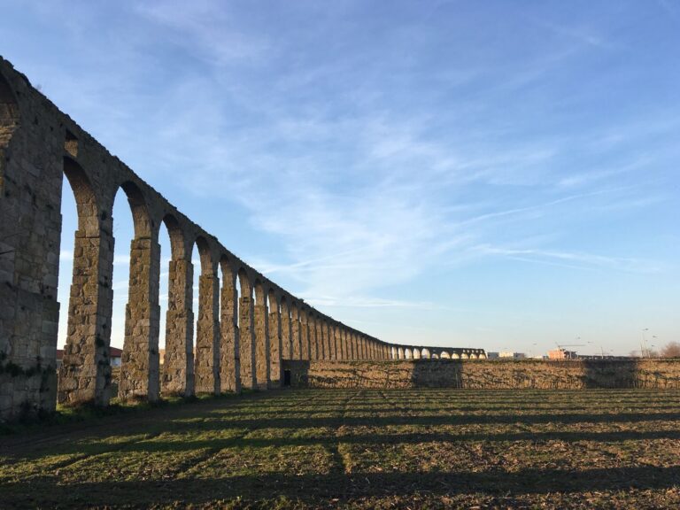 Long stone aqueduct under a clear blue sky in Vila do Conde, Portugal.